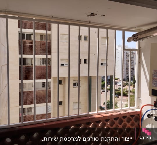 סורגי מתכת על חלון מרפסת עם נוף לבניינים.